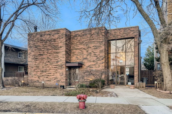 Front view of a brick-faced building with large windows and a small entrance canopy.