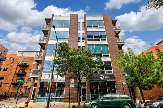 Front view of a multi-story brick building with large glass windows.