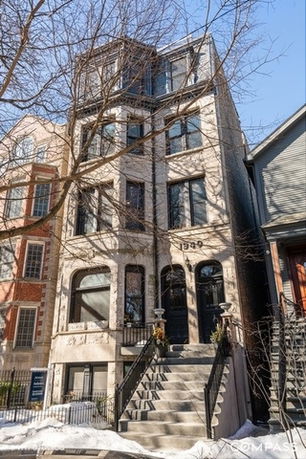 Front view of a multi-story residential building with a staircase leading to the entrance.