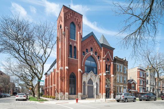 Front view of a large brick building with arched windows and decorative stonework.
