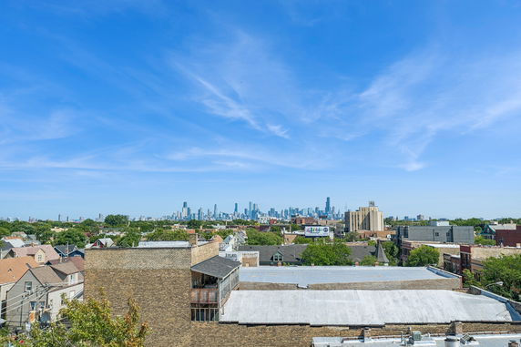 Wide angle view of buildings with a distant city skyline under a blue sky.