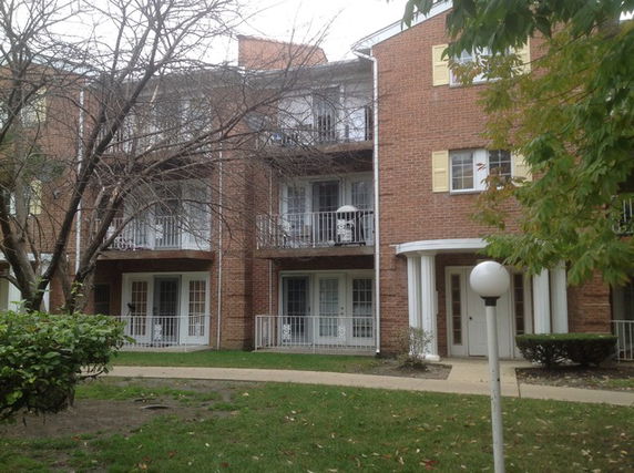Front view of a multi-story brick building with balconies and white railings.