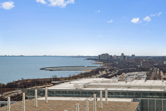 Wide view of a coastal cityscape with a large water body and high-rise buildings in the distance.