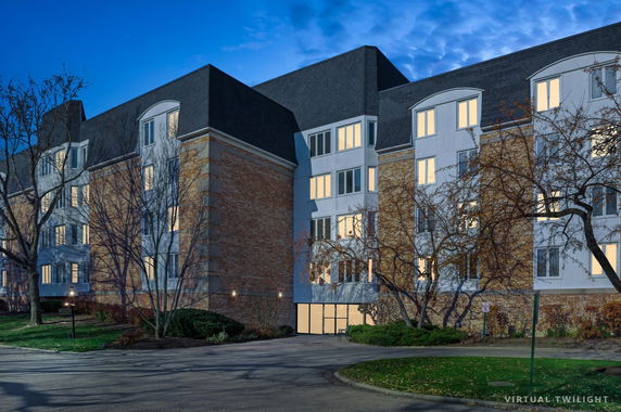 Front view of a multi-story building with large windows and brick facade.