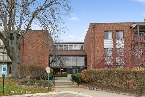 Front view of a multi-story brick building with large windows and entrance.