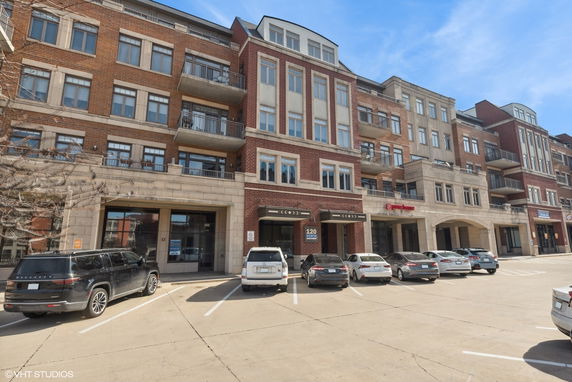 Front view of a multi-story brick building with parking spaces in front.