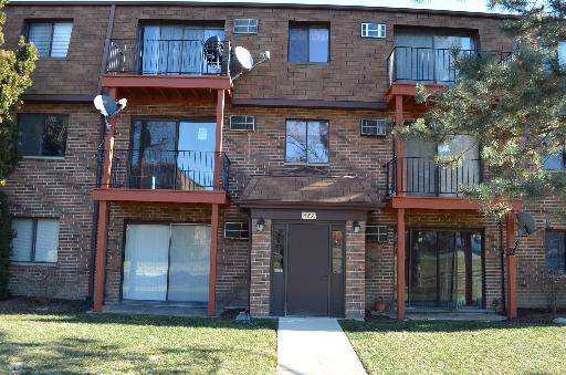 Front view of a multi-story brick apartment building with multiple balconies and satellite dishes.