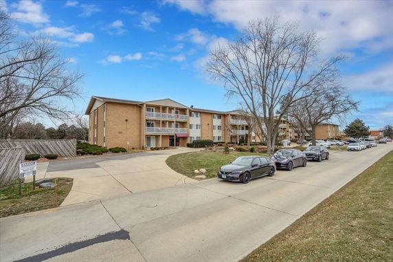 Front view of a multi-story apartment building with balconies and parking.