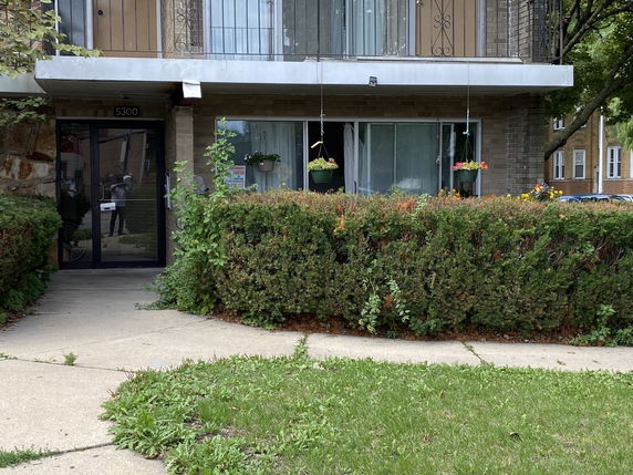 Front view of a two-story building entrance with glass doors and a balcony.