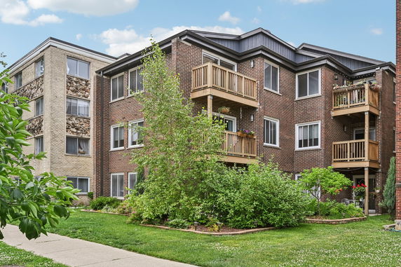 Front view of a multi-story brick apartment building with balconies.