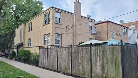 Front view of a two-story brick building with a fenced yard.
