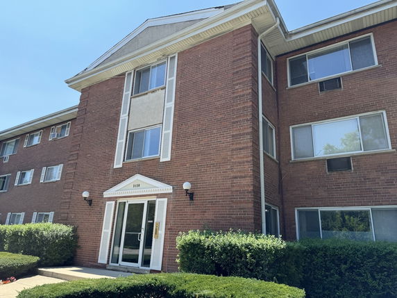 Front view of a multi-story brick apartment building with multiple windows.