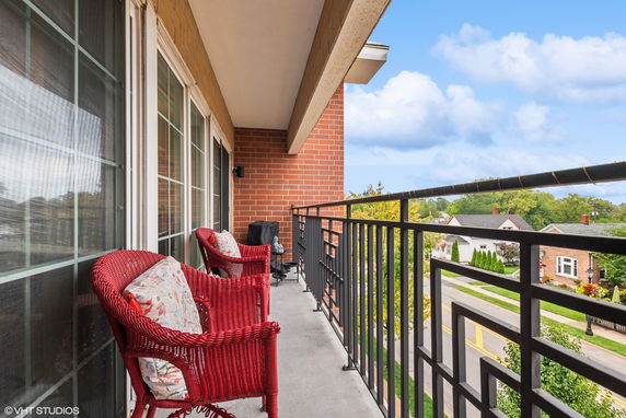 Balcony with red wicker chairs and view of surrounding neighborhood.