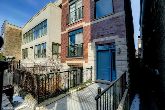 Front view of a multi-story house with brick and stone facade and a blue door.