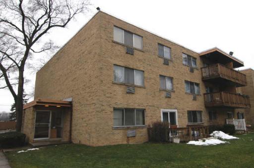 Front view of a brick three-story apartment building with balconies.