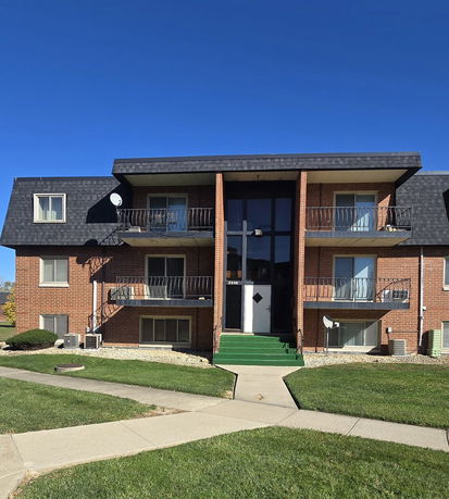 Front view of a multi-story brick apartment building with balconies.