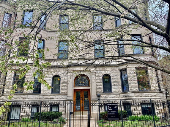Front view of a multi-story stone building with arched windows and an ornate entrance.
