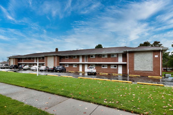 Front view of a two-story brick building with a parking area.