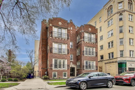 Front view of a brick multi-story building with balconies.