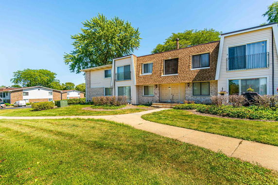 Front view of a two-story residential building with multiple entrances and a landscaped yard.