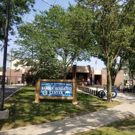 Front view of a community aquatic center building with a sign for the Village of Elmwood Park Family Aquatic Center.