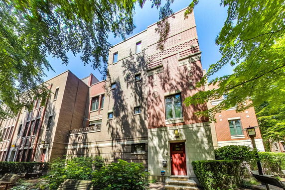 Front view of a multi-story brick building with a red door.