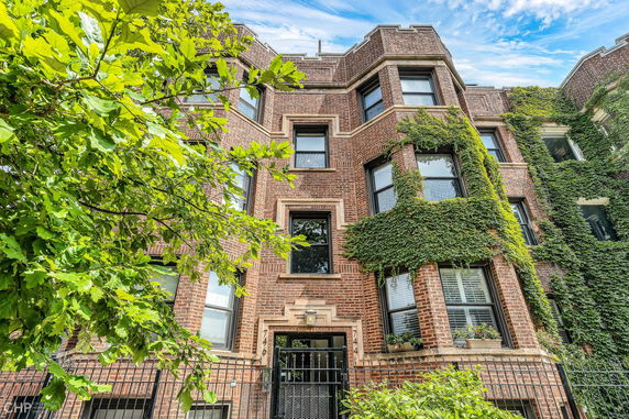 Front view of a multi-story brick building with ivy-covered walls and multiple windows.