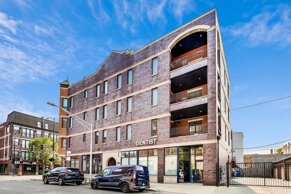 Front view of a multi-story brick building with balconies and a dental office on the ground floor.
