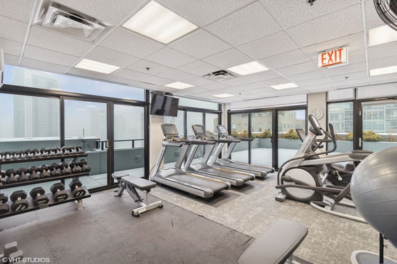 Interior view of a gym with exercise equipment and large windows.
