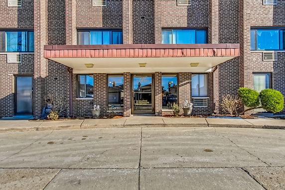 Front view of a brick building entrance with large windows.