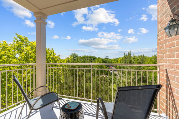 View from a balcony with chairs overlooking trees and a distant water tower.