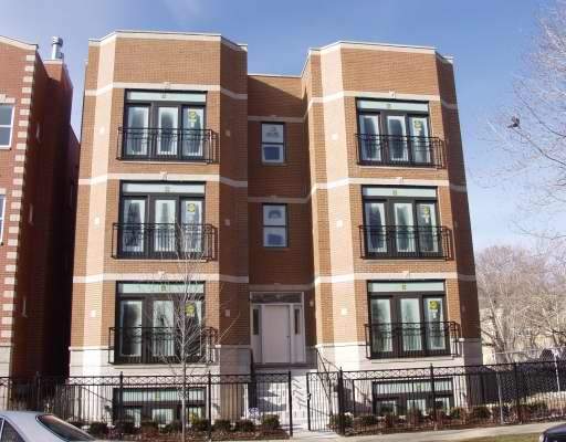 Front view of a multi-story brick building with symmetric windows and balconies.