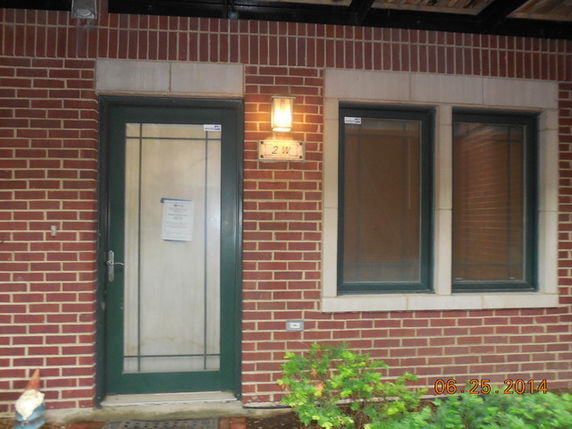 Front view of a house with a glass door and two windows on a brick wall.