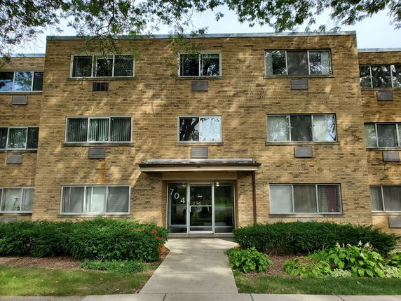 Front view of a three-story brick apartment building with multiple windows and a central entrance.