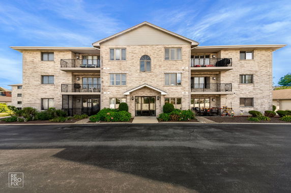Front view of a three-story apartment building with a brick exterior and balconies.