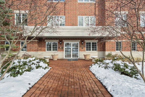 Front view of a brick building entrance with glass doors and windows.