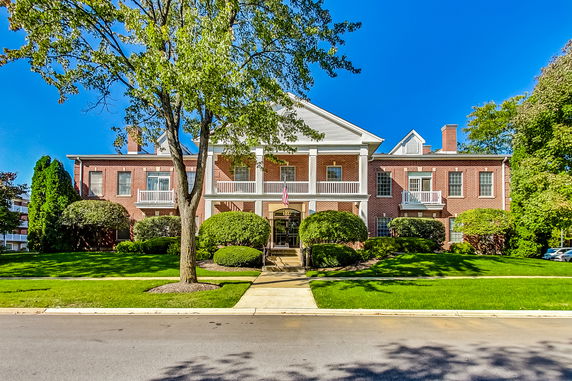 Front view of a large two-story brick building with columns and a central entrance.