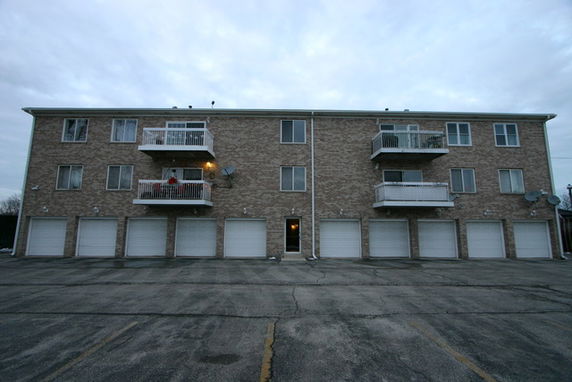 Front view of a two-story apartment building with balconies and garage doors.