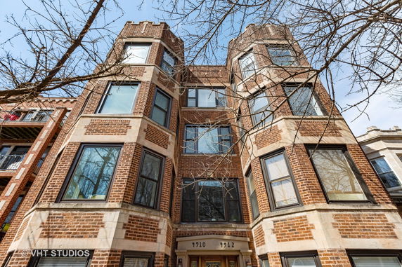 Front view of a multi-story brick building with large windows.