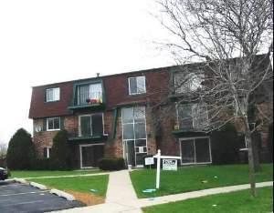 Front view of a multi-story apartment building with brick facade and balconies.