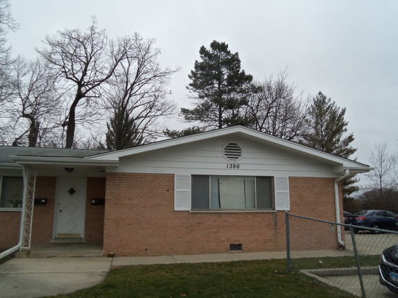 Front view of a single-story house with brick facade and a gable roof.