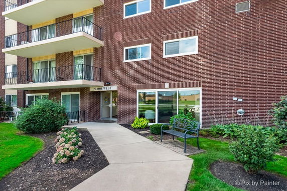 Front view of a multi-story brick building with balconies and an entrance labeled 5300 West.