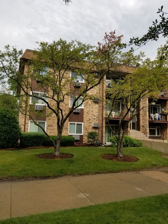 Front view of a multi-story brick apartment building with balconies.