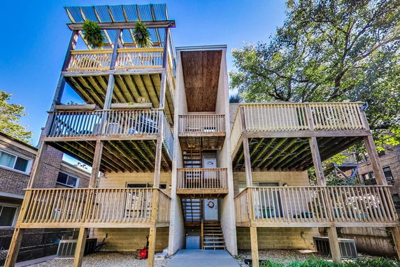 Rear view of a multi-story building with wooden balconies and a staircase.