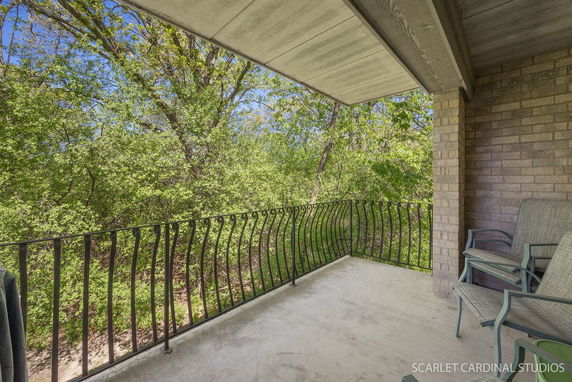 View from a balcony with ornate railing overlooking lush green trees.
