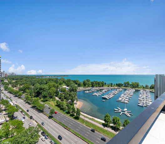 Panoramic view of a marina with boats and a distant city skyline.