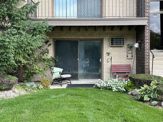 Front view of a house with a sliding glass door and a small outdoor seating area.