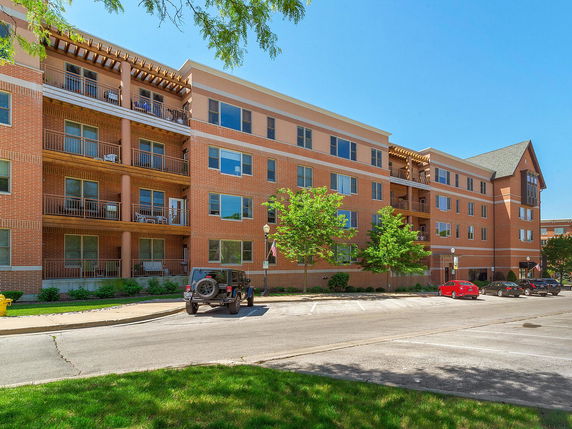 Front view of a multi-story brick apartment building with balconies.