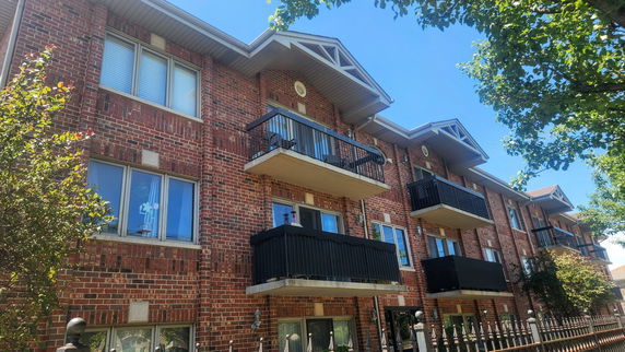 Front view of a multi-story brick apartment building with balconies.