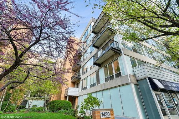 Front view of a modern multi-story building with balconies and large windows.